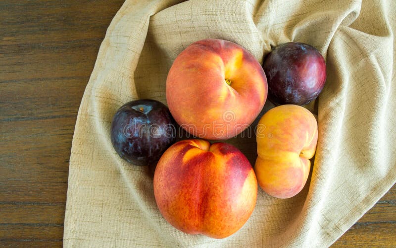 Group of peaches and plums on a beige napkin