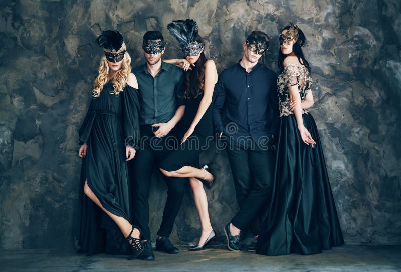 Group of people in masquerade carnival mask posing in studio. Beautiful women and men wearing venetian mask. Fashion, party, friends concept