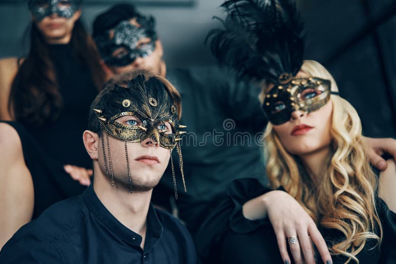 Group of people in masquerade carnival mask posing in studio. Beautiful women and men wearing venetian mask. Fashion, party, friends concept