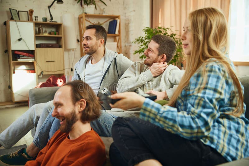 Group portrait of guys and girl sitting in living room and spending all time watching new films with funny, unexpected stock photos
