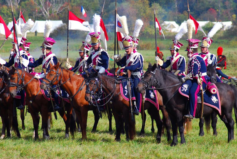 A group of reenactors dressed as Napoleonic war soldiers ride horses royalty free stock images