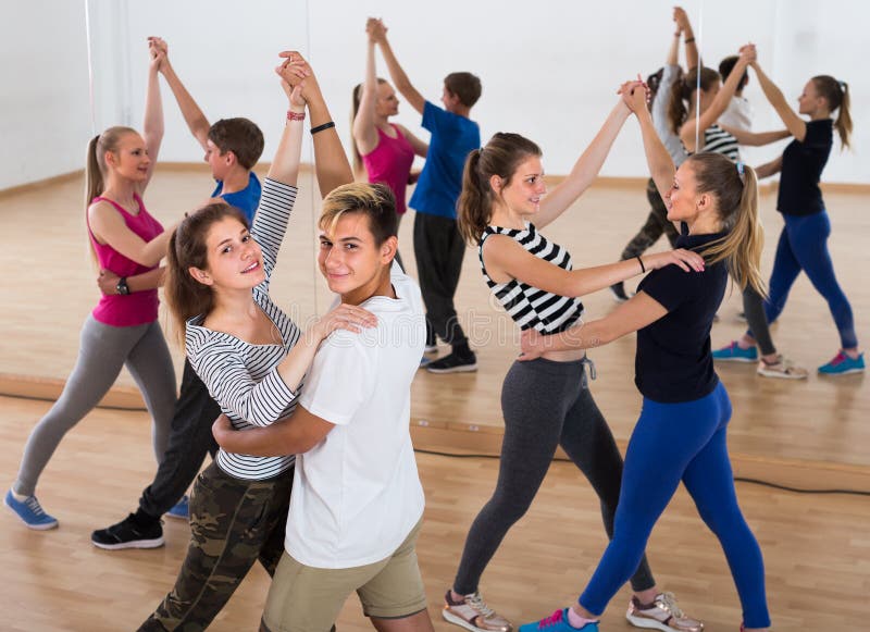 Group of satisfied teenagers dancing tango in dance studio