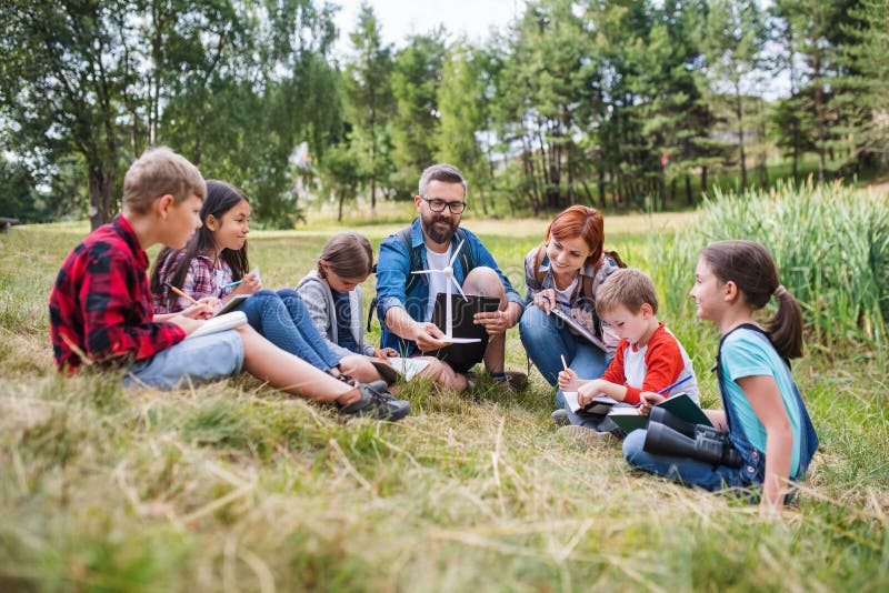Group of school children with teacher and windmill model on field trip in nature. stock photos Group of school children with teacher and windmill model on field trip in nature. stock photos