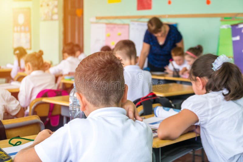 group of school kids sitting and listening to teacher in classroom from back royalty free stock photography group of school kids sitting and listening to teacher in classroom from back royalty free stock photography