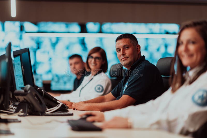 Group of Security data center operators working in a CCTV monitoring room looking on multiple monitors Officers royalty free stock photography