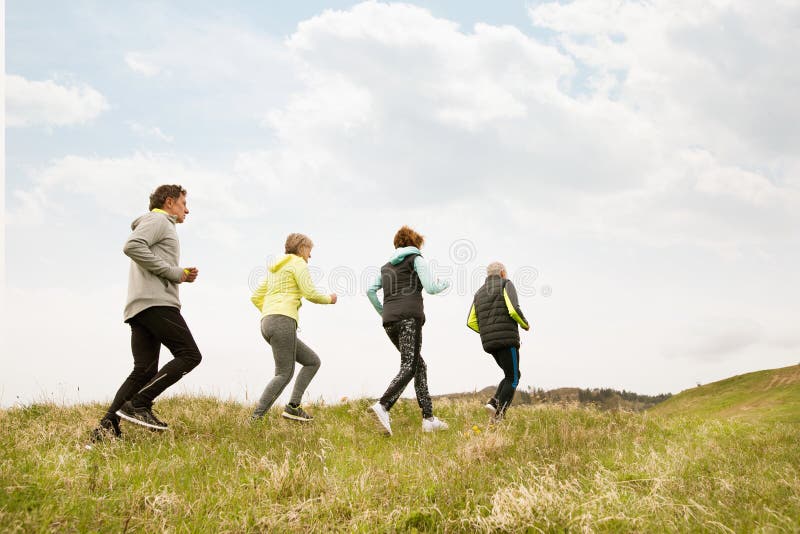 Group of seniors running outside on the green hills.