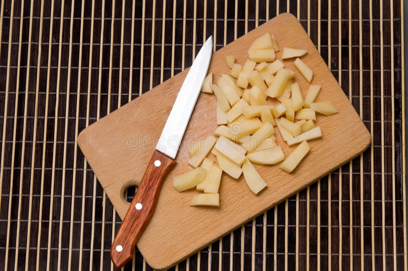 A Group of Sliced Potatoes on a Wood Cutting Board with a Sharp Stock