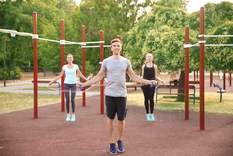 Group of sporty people jumping rope on athletic field outdoors stock photography Group of sporty people jumping rope on athletic field outdoors stock photography