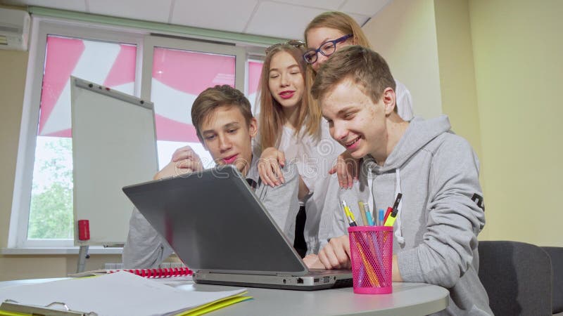 Group of teen students working on laptop together