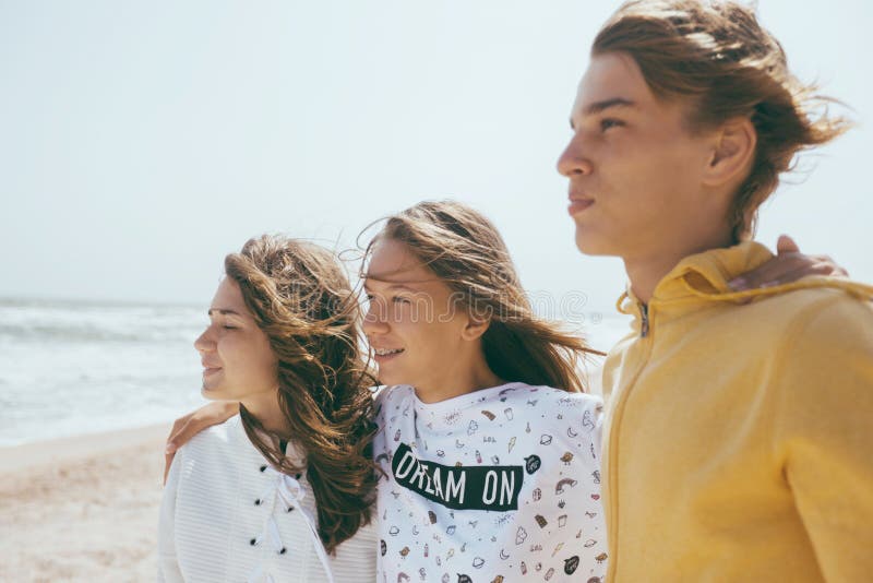 Group of teenage friends having fun on the beach. Hipster boy and girls playing outdoors. Teen girl smiling with dental braces. Group of teenage friends having fun on the beach. Hipster boy and girls playing outdoors. Teen girl smiling with dental braces.