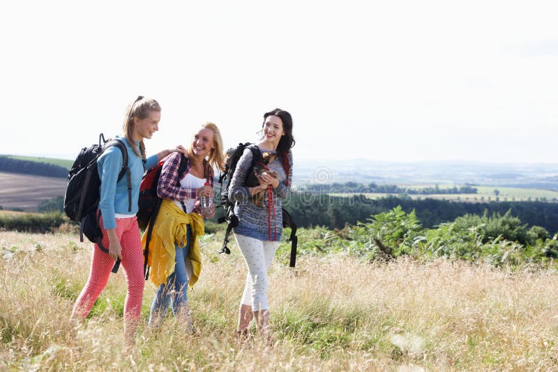 Group Of Teenage Girls Hiking In Countryside With Dog