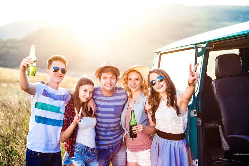 Group of teenage hipsters on a roadtrip, drinking beer royalty free stock photos Group of teenage hipsters on a roadtrip, drinking beer royalty free stock photos