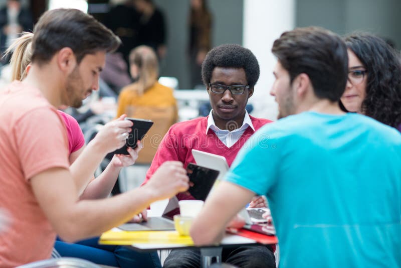 A Group of Teenagers Sitting at the Table in Cafe, Using Laptop and Drinking Orange Juice. Stock