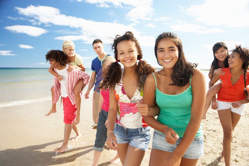 Gruppo di adolescenti a piedi lungo la spiaggia sorridente.