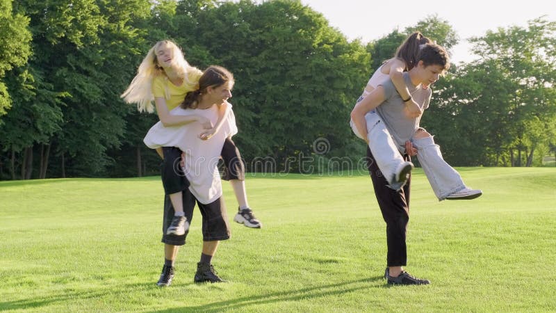 Group of teenagers 16, 17 years old are having fun together in summer in park on green lawn