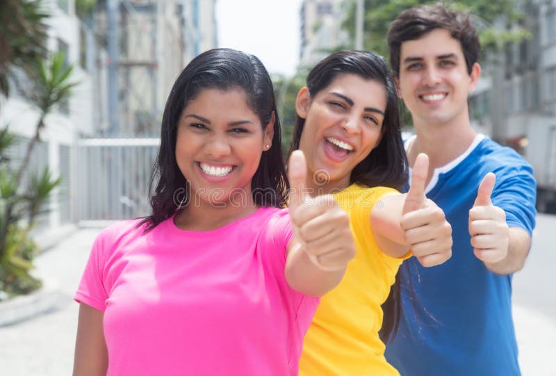 Group of three young people in colorful shirts standing in line and showing thumbs royalty free stock photos Group of three young people in colorful shirts standing in line and showing thumbs royalty free stock photos
