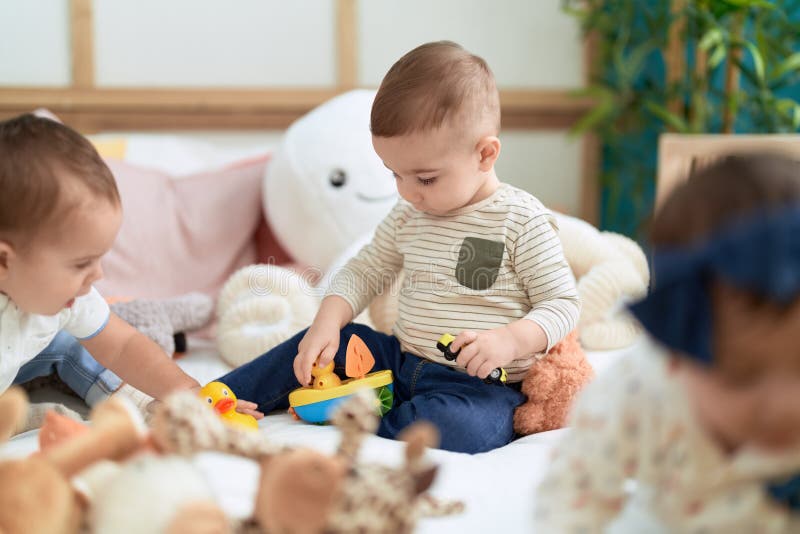 Group of Toddlers Sitting on Bed Playing with Toys at Kindergarten