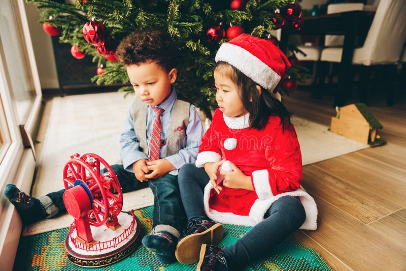 Two adorable 3 year old kids playing by the Christmas tree royalty free stock images Two adorable 3 year old kids playing by the Christmas tree royalty free stock images