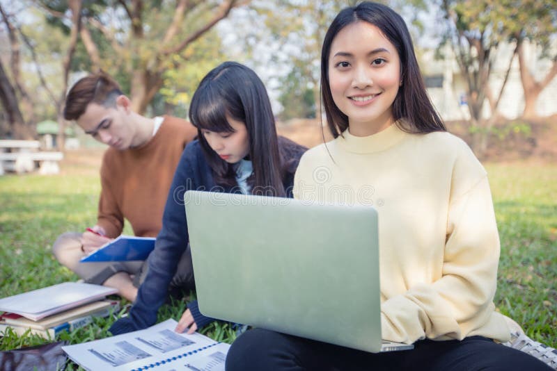 Group Of University Students asian sitting on the green grass W royalty free stock photography Group Of University Students asian sitting on the green grass W royalty free stock photography