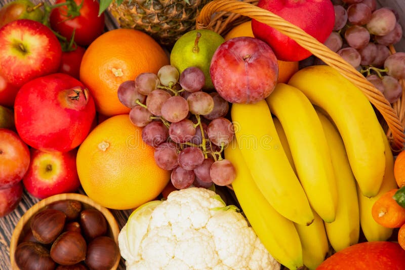 Group vegetables and Fruits Apples, grapes, oranges, and bananas in the wooden basket with carrots, tomatoes, guava, chili, eggpla