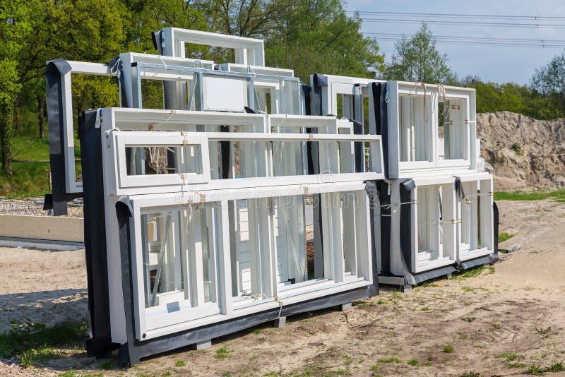 Group of white wooden window frames stand outside