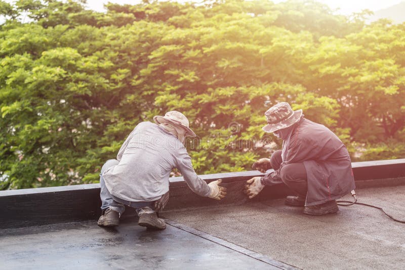 Group of worker installing tar foil on the rooftop of building.