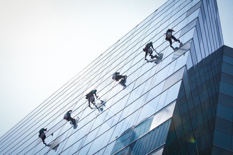 Grupo de trabajadores limpieza ventanas servicio sobre el alto crecimiento el edificio.