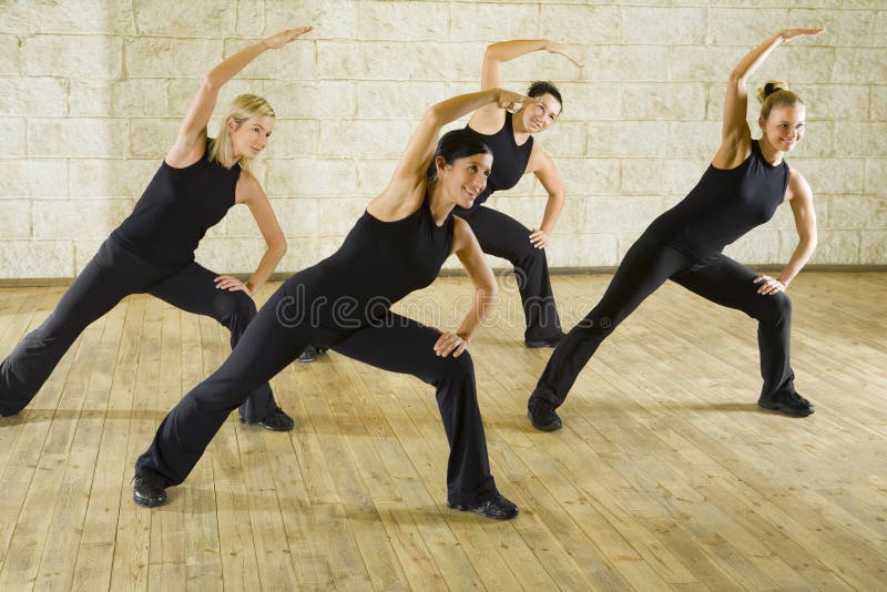 A group of women exercising in the fitness club. They're smiling. Front view. A group of women exercising in the fitness club. They're smiling. Front view.