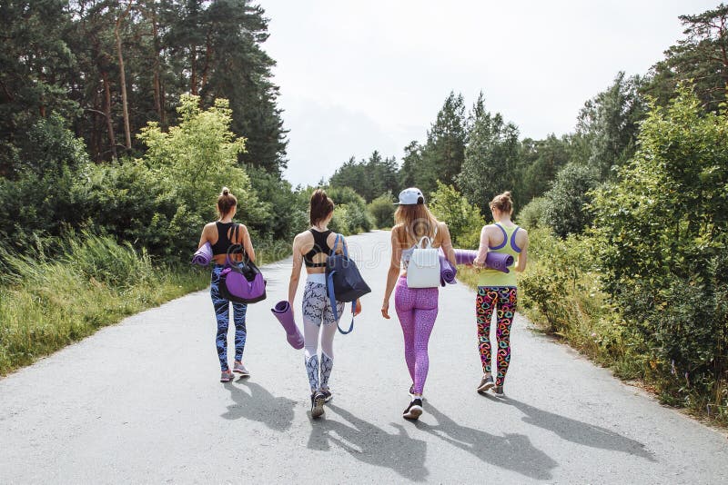 Group of young attractive women friends with sports equipment going for a workout in the Park