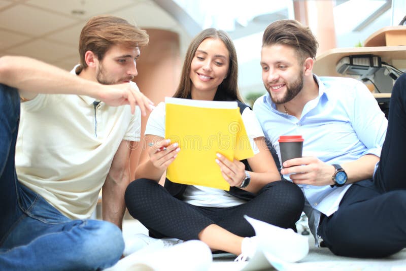 Group of young business people and designers looking at project plan laid out on floor. They working on new project. stock image Group of young business people and designers looking at project plan laid out on floor. They working on new project. stock image
