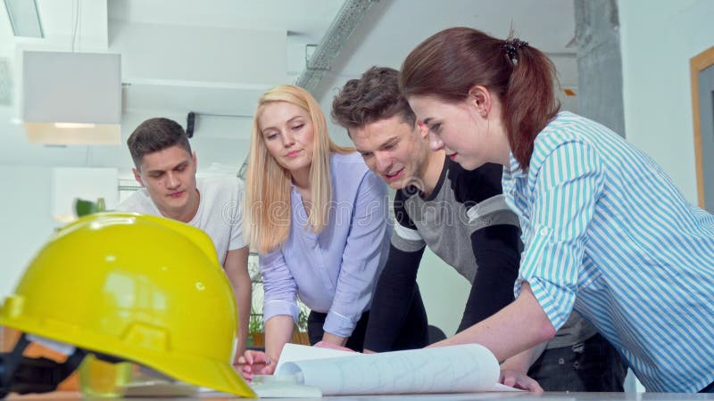 Group of young engineers discussing architectural blueprints