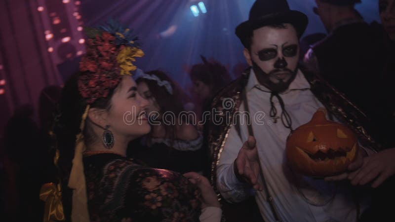 Group of young friends in costumes dancing at night club halloween party