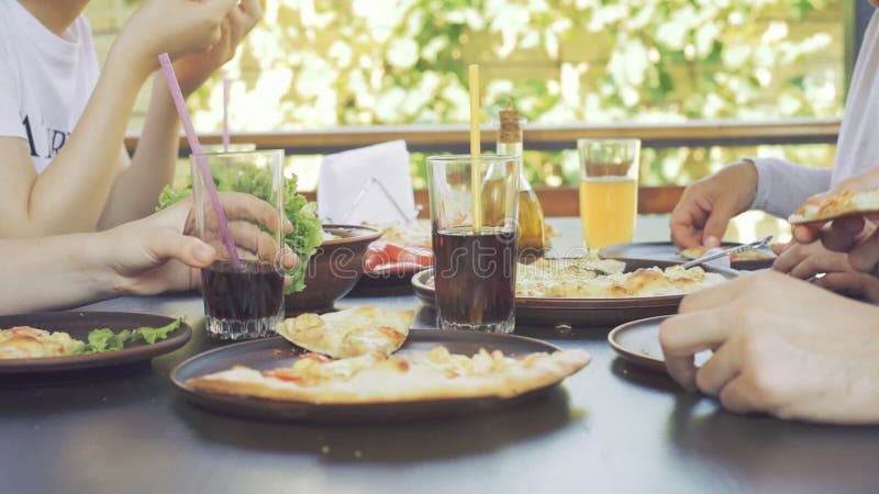 Group of young friends enjoying a meal, eating pizza.