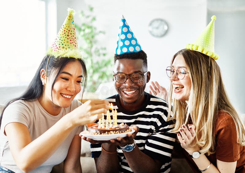 Group of young happy people friends having fun blowing candles on a birthday cake at home. Group of young happy people friends having fun blowing candles on a birthday cake at home