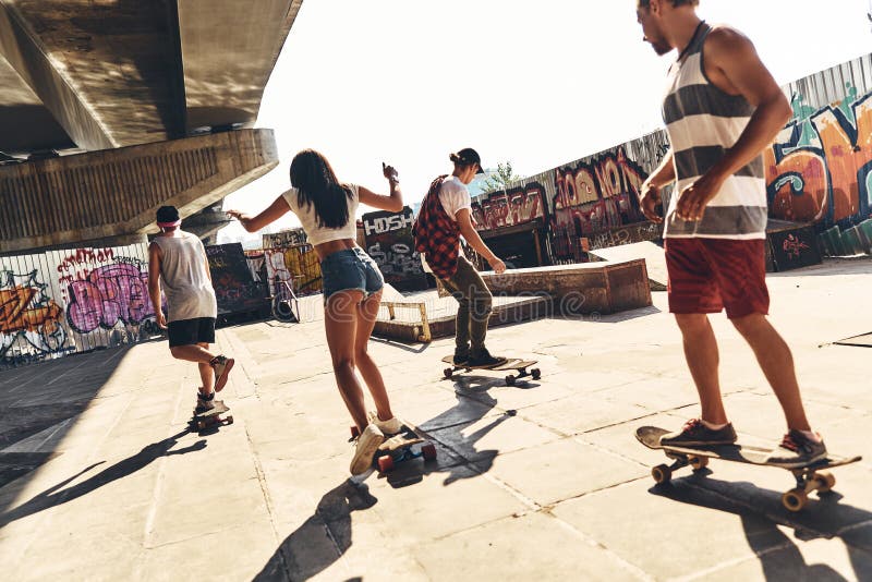 Group of young modern people skateboarding together outdoors. Group of young modern people skateboarding together outdoors