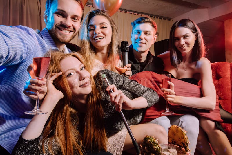 Group of young people gathered to sing songs in karaoke bar, enjoy celebration of birthday in karaoke, young guys and ladies together at party. Group of young people gathered to sing songs in karaoke bar, enjoy celebration of birthday in karaoke, young guys and ladies together at party