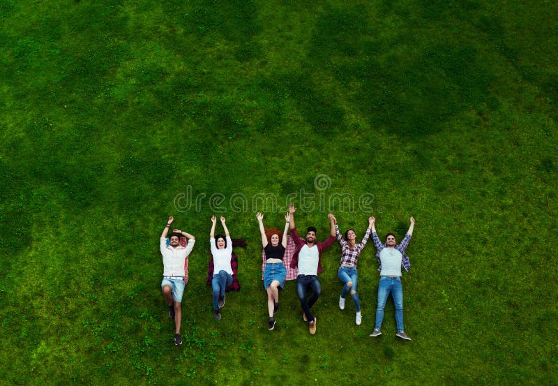 Group of young people laying on the grass, smiling