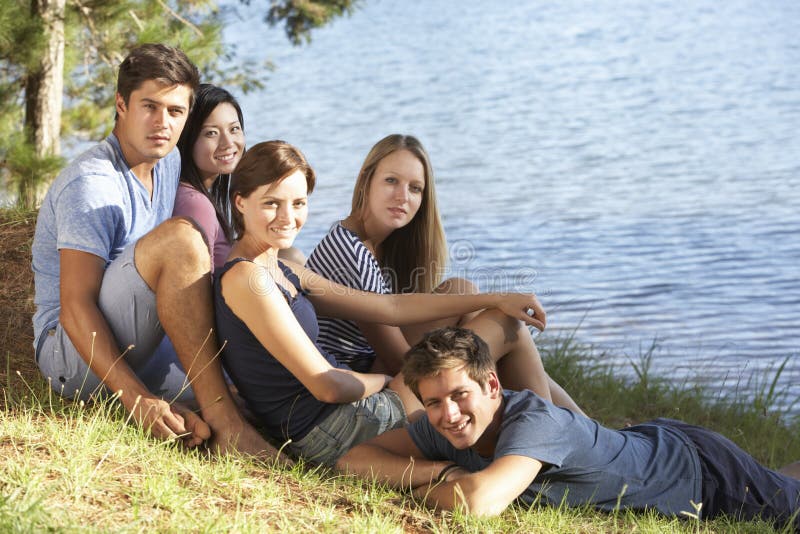 Gruppo Di Giovani Seduti In Riva Al Lago.