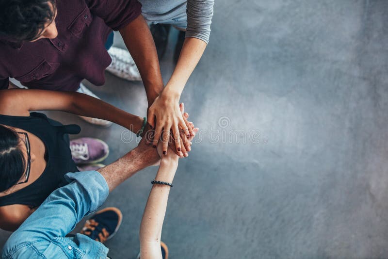 Top view image of group of young people putting their hands together. Friends with stack of hands showing unity. Top view image of group of young people putting their hands together. Friends with stack of hands showing unity.