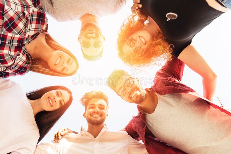 Grupo de joven de pie en círculo, afuera, divirtiéndose.