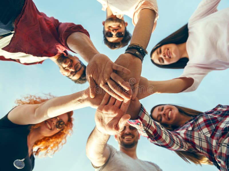 Group of young people standing in a circle, outdoors, having fun, hands