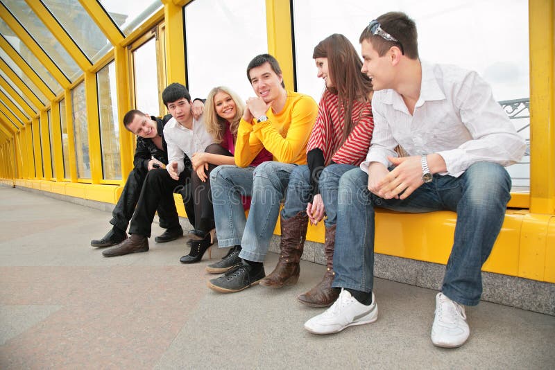 Group of young persons sit on footbridge