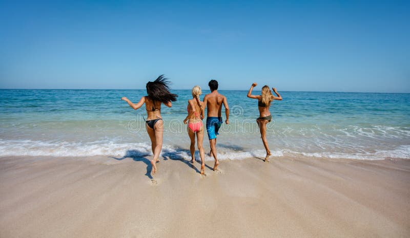 Groupe d'amis courant dans l'eau de mer photo libre de droits Groupe d'amis courant dans l'eau de mer photo libre de droits