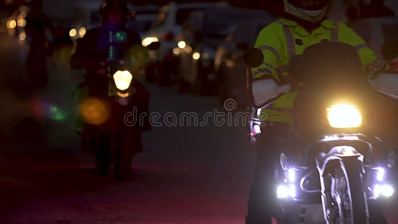 Groupe d'amis de motorbiker conduisant lentement la rue sombre avec les phares lumineux