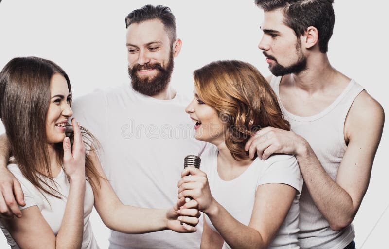 Groupe d'amis jouant le karaoke au-dessus du fond blanc concept au sujet de l'amitié et des personnes photo libre de droits Groupe d'amis jouant le karaoke au-dessus du fond blanc concept au sujet de l'amitié et des personnes photo libre de droits