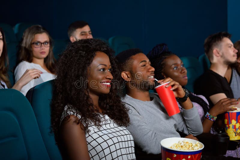 Enjoying a great movie with closest ones. Portrait of a group of young friends smiling while watching a movie at the cinema together. Enjoying a great movie with closest ones. Portrait of a group of young friends smiling while watching a movie at the cinema together