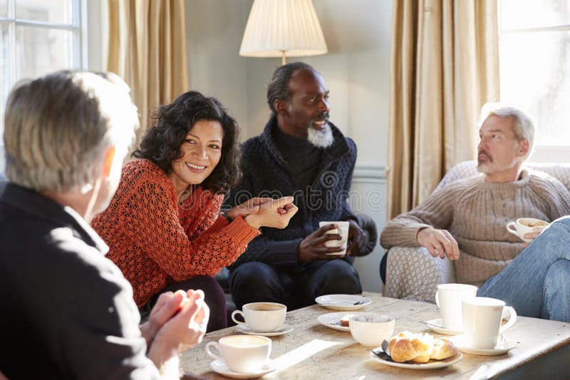 Groupe d'amis âgés par milieu se réunissant autour du Tableau dans le café photos libres de droits