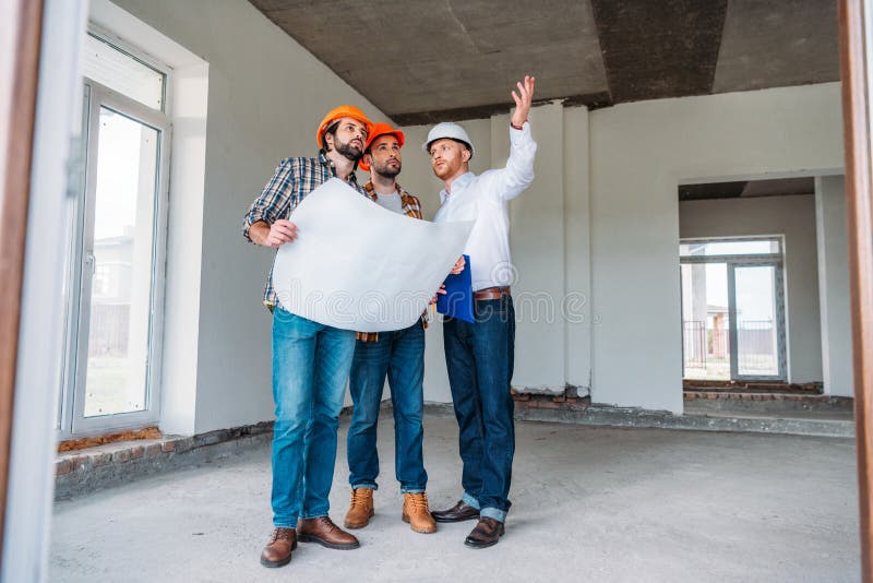 Groupe d'architectes avec le modèle ayant la conversation et regardant loin l'intérieur de photographie stock