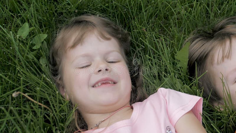 Groupe d'enfants heureux allongés sur l'herbe verte en plein air dans le parc de printemps clips vidéos