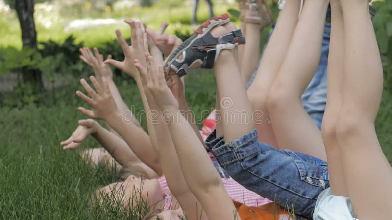 Groupe d'enfants heureux allongés sur l'herbe verte en plein air dans le parc de printemps banque de vidéos